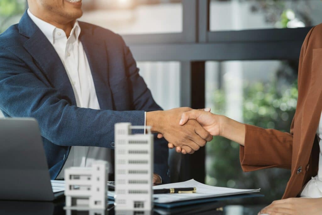 Close up shake hands, Considering buying a home, investing in real estate.